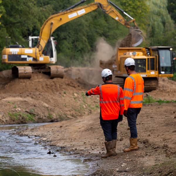 2 hommes de dos en tenue de chantier en face d'engins de chantier | Equo Vivo - Nous connaître