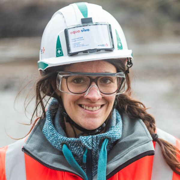 Femme en tenue de chantier portant un casque Equo Vivo souriant à l'objectif | Equo Vivo - Page d'accueil